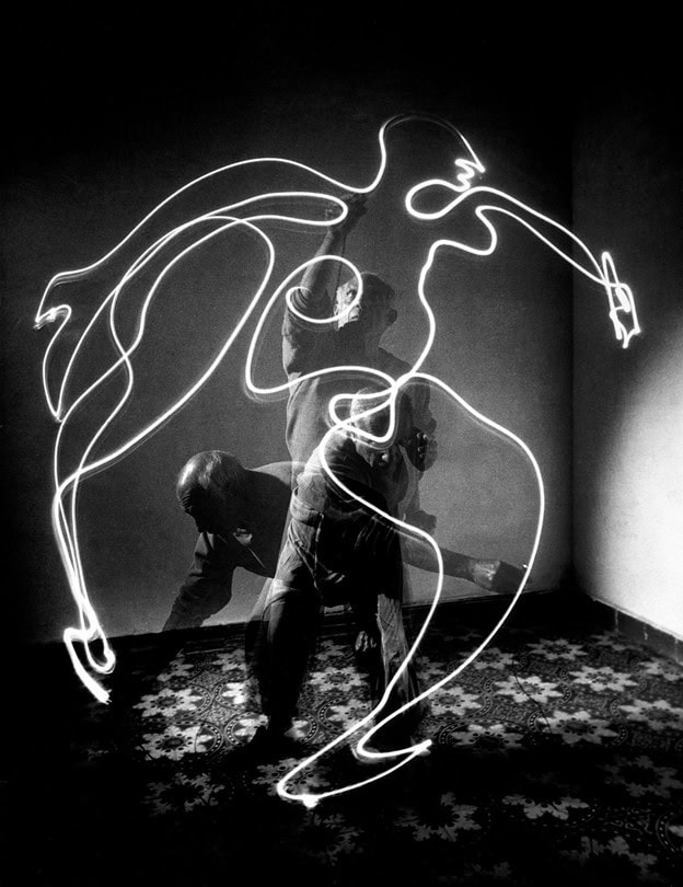 Black-and-white long exposure photograph showing Pablo Picasso creating a glowing centaur figure with light painting techniques