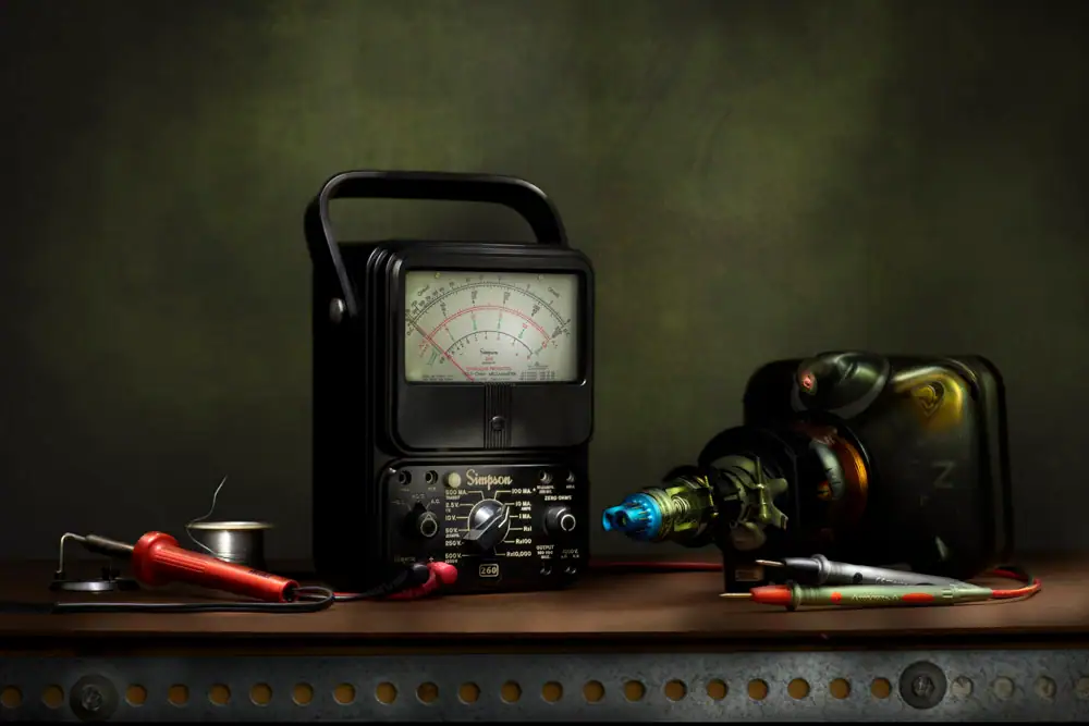 Still-life light painting titled End of an Era: The Cathode Ray Tube featuring a vintage Simpson analog meter, soldering iron, test probes, and a disassembled cathode ray tube arranged on a workbench against a dark green background. The composition reflects the decline of analog electronics and the passing of a technological era.