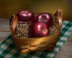 Fresh red apples in a woven basket, perfect for healthy snacks and fruit salads. Three Apples in a Wicker Basket by Bobby Izquierdo