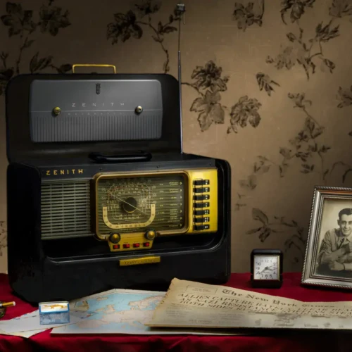 Classic retro radio setup with personal memorabilia and decorative elements. Vintage Zenith radio with framed photograph and nostalgic items on a red tablecloth.